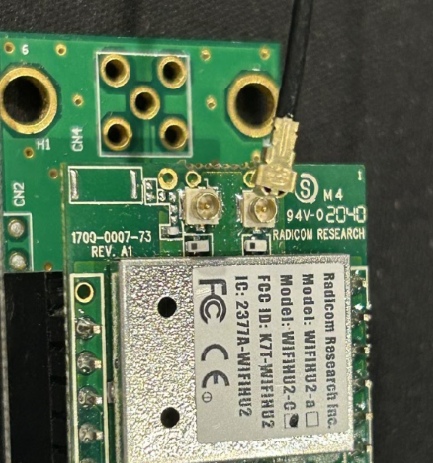 A green circuit board with a black wire

Description automatically generated