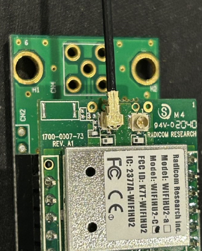 A green circuit board with a black wire
Description automatically generated