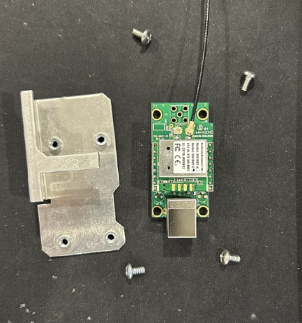 A small green circuit board with a black wire and screws
Description automatically generated